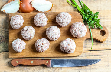 Raw meatballs on the wooden cutting board. Top view