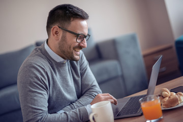 Man sitting on floor while watching laptop at home