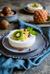 Unbaked mini cheesecakes topped with pineapple, kiwi and pomegranate
