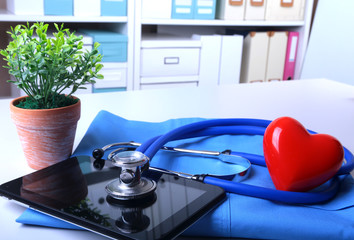 Doctor coat with medical stethoscope and red heart on the desk