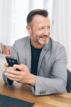 Smiling man using phone while sitting at table