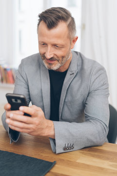 Mature man using smartphone while sitting at table