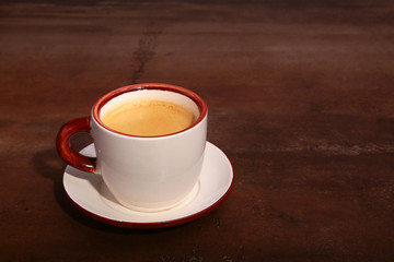 A cup of espresso coffee on a dark wooden background