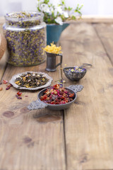 Tea in bags and a jar with dry tea. Lavender and other dried flowers and herbs. Wooden out. Ingredients for tea. Text