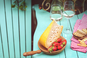 Dutch cheese and strawberries. White wine two glasses. A table with a snack at a party. Place for text