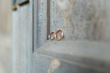 Wedding rings on a wooden door in the corner. Wedding rings hanging on rope over wooden background. Vintage image.
