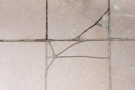 Cracked ceramic tiles and fugue outer terrace floor surface due to improper residential construction material and moisture