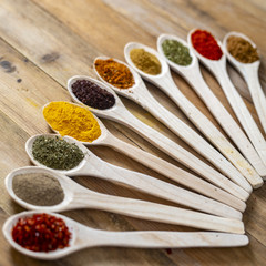 Assorted spices on wooden spoons. Delicious food ingredients.