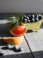 horizontally creative concept for summer with bath with blueberry and palm branch, pieces of grapefruit