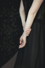 woman in black dress holding her hands at her back, sensual studio shot, can be used as background - obrazy, fototapety, plakaty