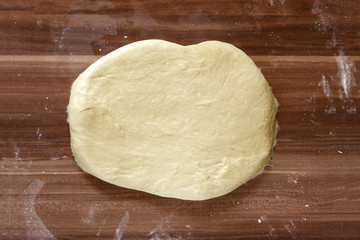 Overhead view of freshly rolled out dough and a retro wooden rolling pin during the preparing of...