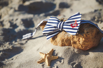 Stylish bow tie on stone at the beach. Men's and women's accessories on the sandy beach background