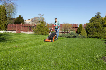 teenage girl working in garden, mowing grass with lawn-mower