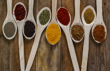 Assorted spices on wooden spoons. Delicious food ingredients.