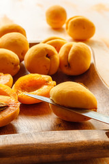The process of manual cleaning of apricots from bones using a kitchen knife on a wooden dish. Preparation for cooking jam. Lifestyle