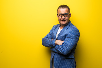 Fototapeta premium Portrait of happy fun middle age man in suit and eyesglasses isolated on yellow background