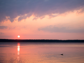 The sun rises over a quiet forest lake