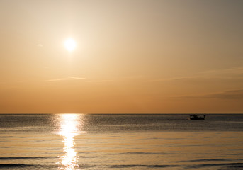 Obraz premium golden hour on the beach with a boat against the light