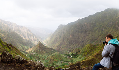 Fototapeta na wymiar Traveler in front of motion landscape. Deep clouds above green Xo-Xo Valley. Santo Antao Island, Cape Verde