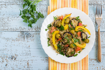 Quinoa with fried eggplants and peppers, tomatoes, olives, parsley