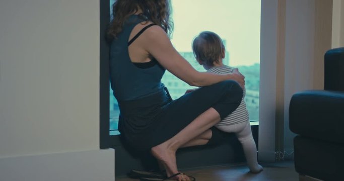 Mother and toddler by window in city apartment