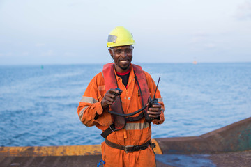 Seaman AB or Bosun on deck of vessel or ship , wearing PPE personal protective equipment - helmet, coverall, lifejacket, goggles. He is smiling. Safety at sea