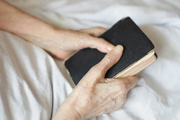 Hands of a senior woman on cane. Senior lying in a bed.