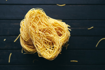 Delicious organic Italian pasta on black wooden table top view 