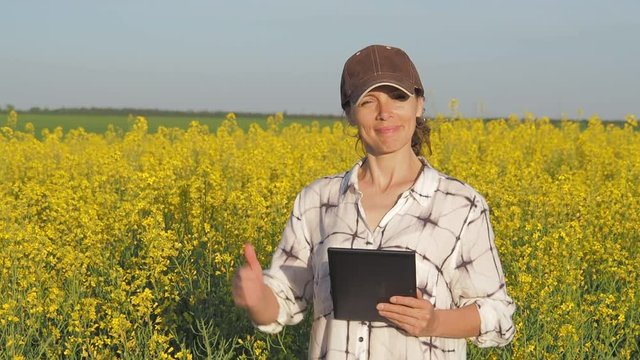 Farmer in a rapeseed field. Happy farmer showing thumb.