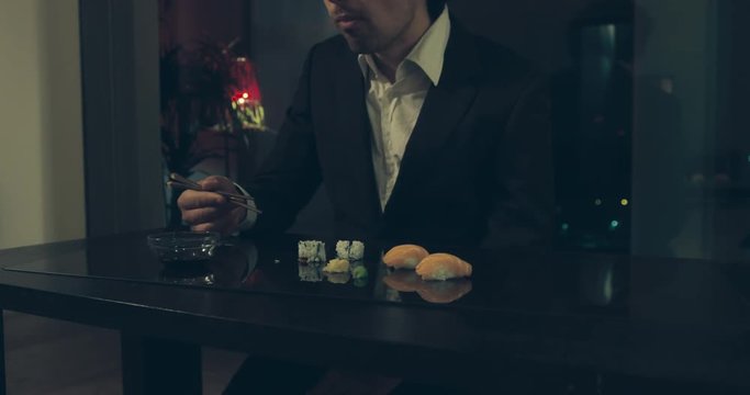 Businessman eating sushi in the city at night