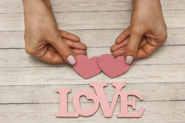 A female hand holds a wooden heart, the concept of love