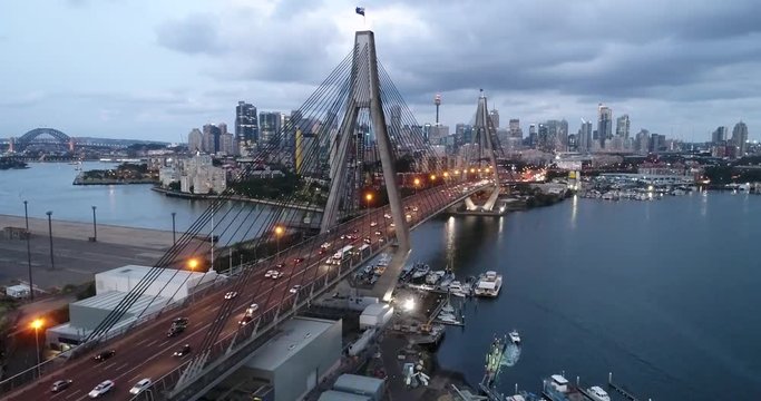 Anzac bridge on Sydney harbour at sunset in aerial flying forward close facing Sydney CBD skyline.
