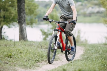 Cycling, sport, outdoor activity and healthy lifestyle. Man riding a bicycle along a path near lake in countryside. 