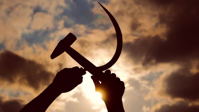 silhouette of a sickle and a hammer against the sky