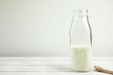 Homemade yogurt salad dressing being poured into a milk bottle