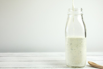 Homemade yogurt salad dressing being poured into a milk bottle