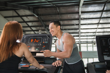 Personal trainer encouraging woman using treadmill