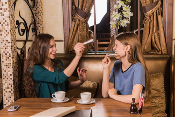 Two happy women plaing with sugar in cafe