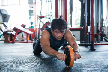 Front view man using abdominal roller 