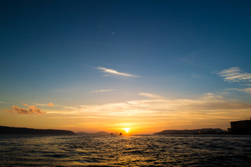 Obraz premium 水平線に沈む太陽と島と船