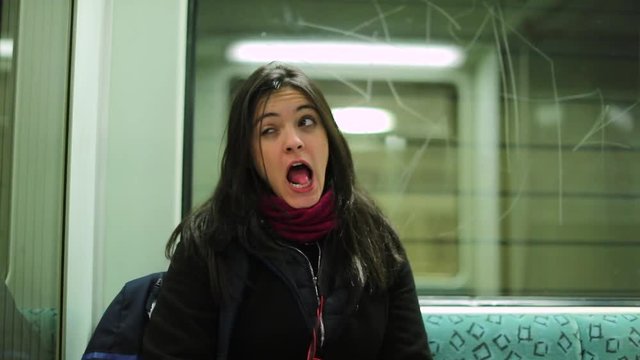 Fun girl doing expressive silly goofy grimaces looking to camera while riding the subway metro