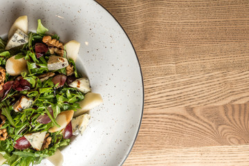 Leaf vegetable salad with cheese, grapes, walnuts and tasty sauce. Healthy, diet food. With copy space