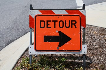 Orange Detour Sign against Striped Barricade along Street