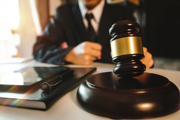 Justice and law concept.Male judge in a courtroom with the gavel,working with,digital tablet computer docking keyboard,eyeglasses,on wood table 
