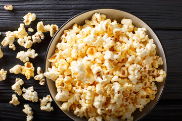 Popular snack: salted popcorn with cheddar cheese and parmesan in a bowl close-up. horizontal top view