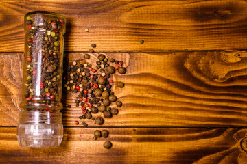 Pepper mill and scattered spices on the wooden table. Top view