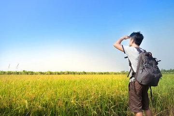 Asian Man backpacker standing and looking rice field with blue sky landscape