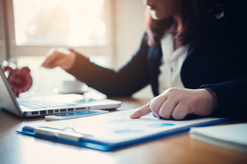 Business woman points to market data on charts.