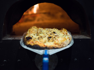 chef removing hot pizza from stove