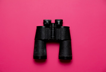 Vintage black binoculars on pink background, High angle view